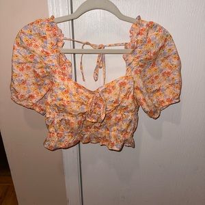 Orange crop top with purple, orange, and yellow flowers. Puffy sleeves. Size: S